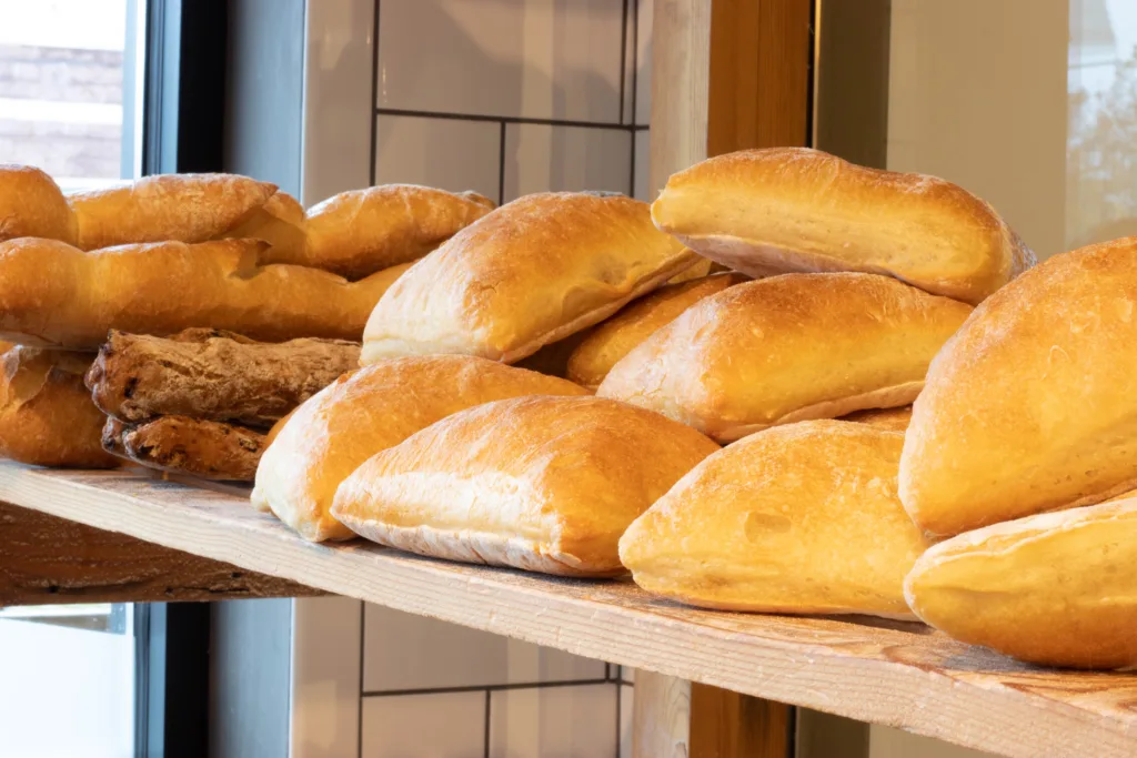Fresh baked rolls stacked on a wooden shelf