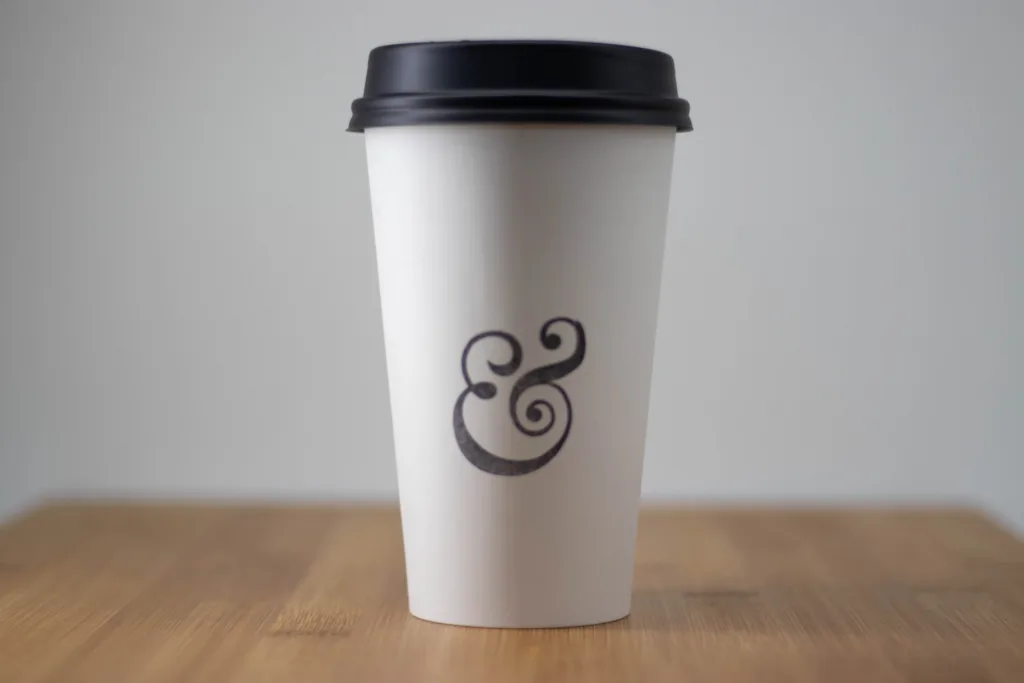 An &grain coffee cup on a wooden table